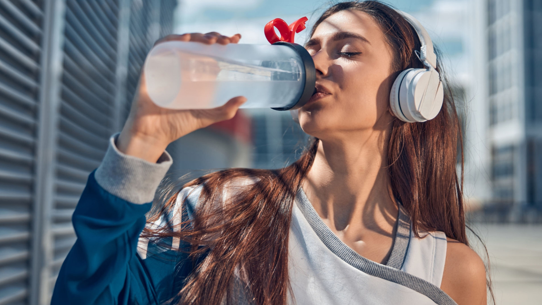Woman drinking from a water bottle of exercising.
